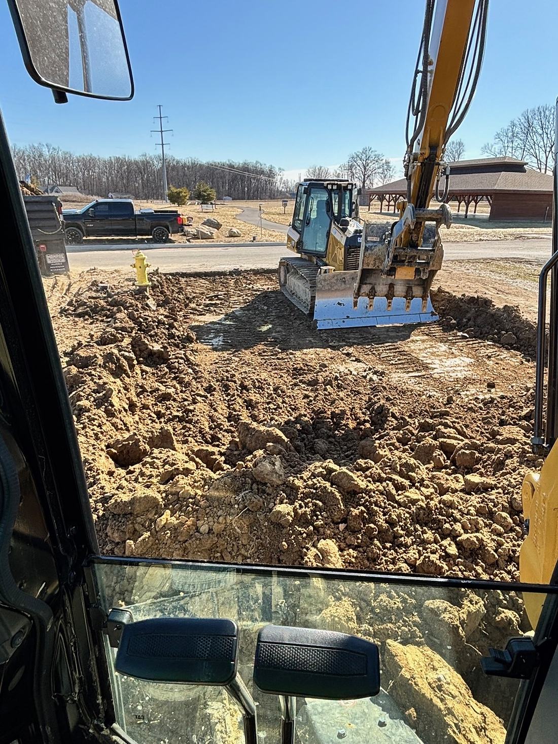 View from a BDX excavator cab of a loaded bucket during earthmoving work