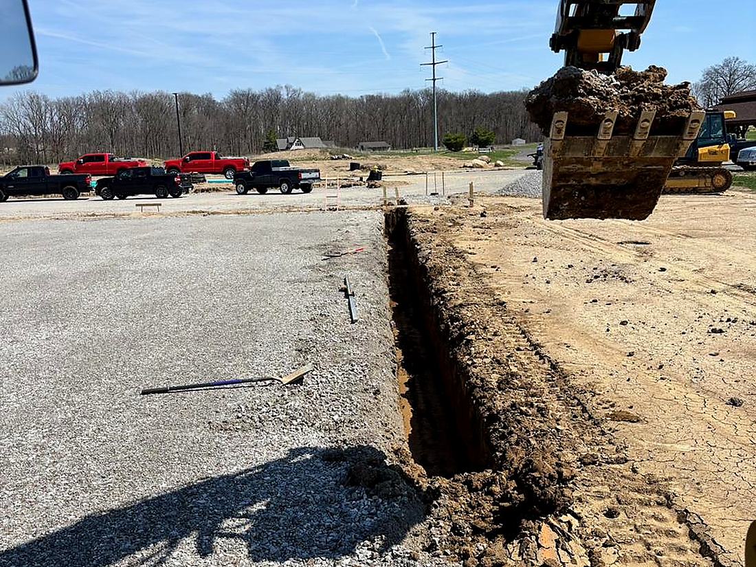 Clean storm trench cut across compacted stone on a BDX commercial site