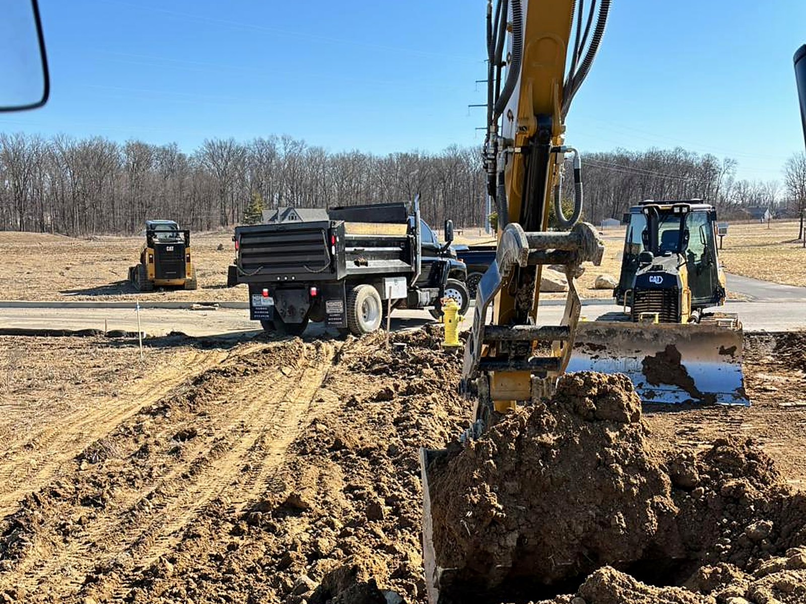 Excavator trenching with dozer grading behind
