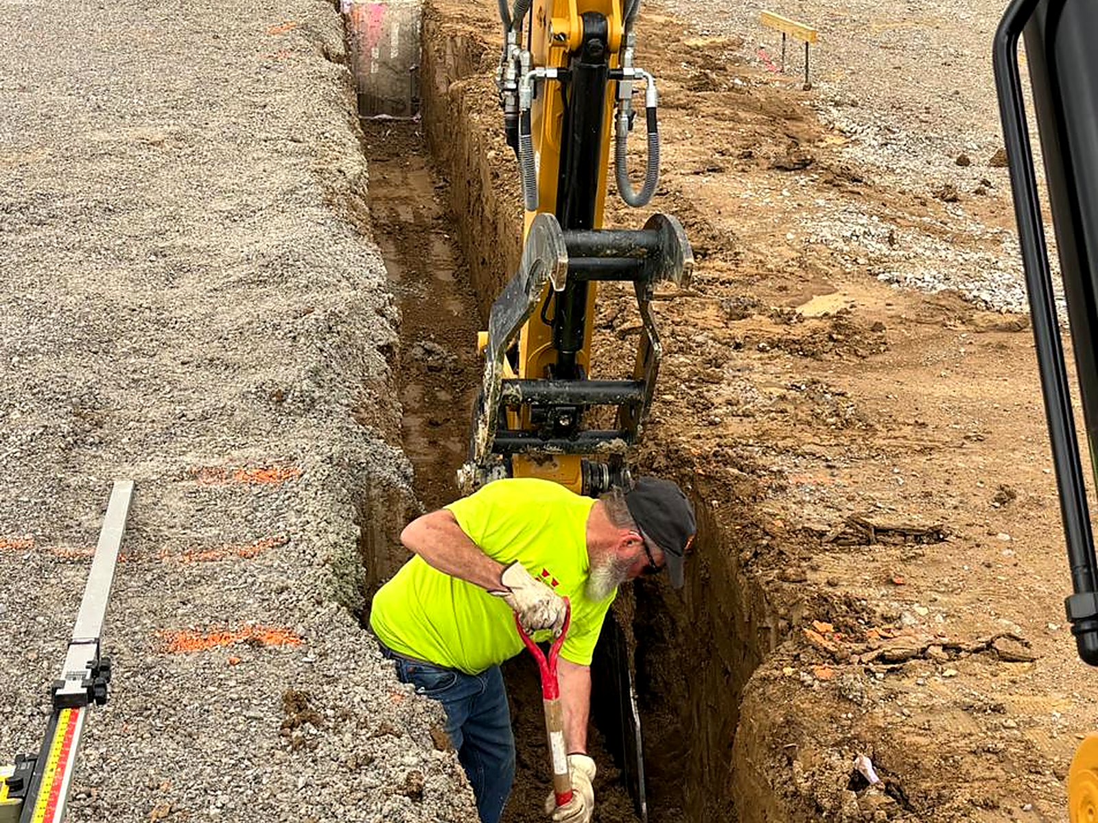 Crew member checking grade in a footing trench