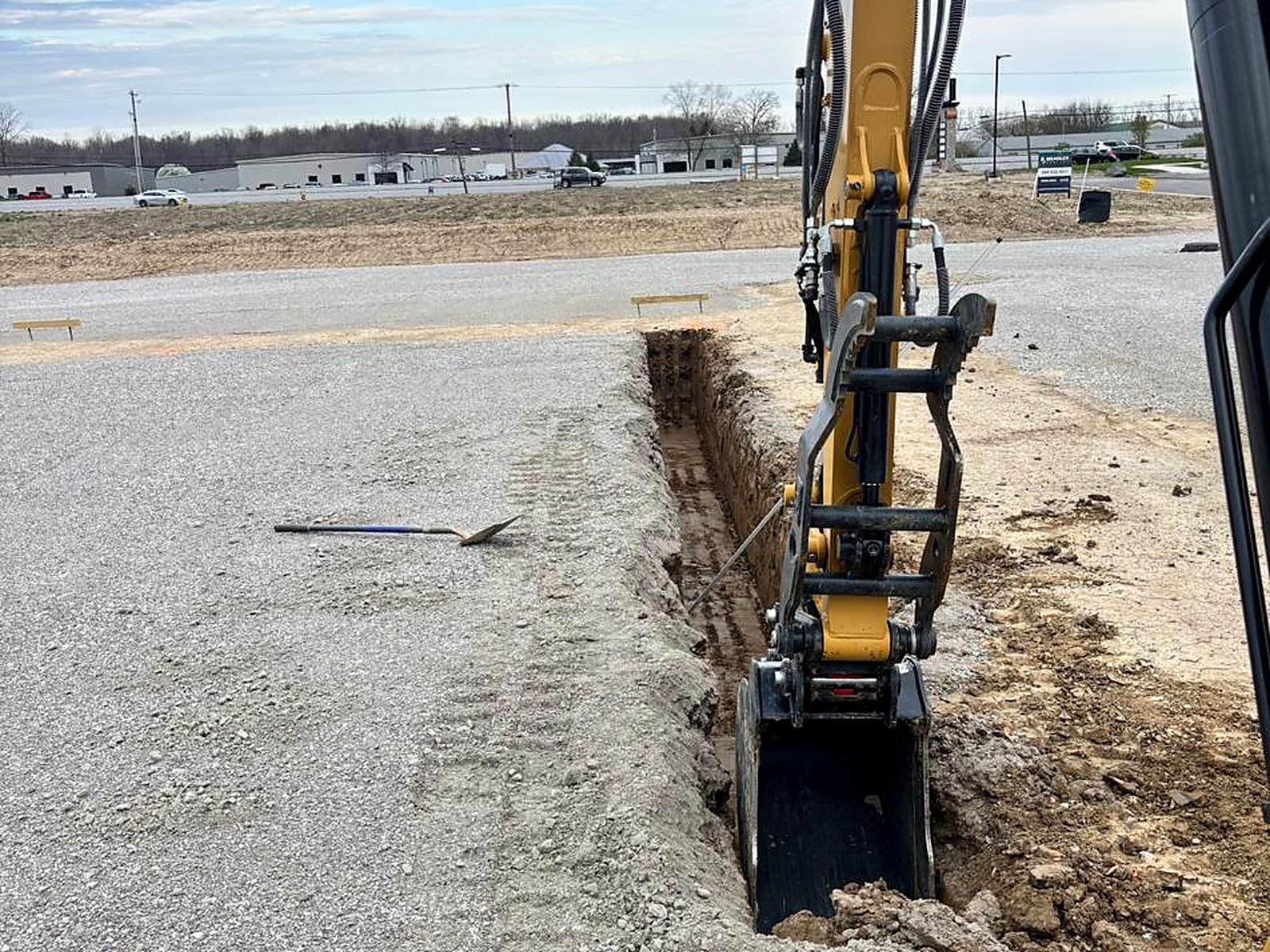 Utility trench cut through a compacted stone pad